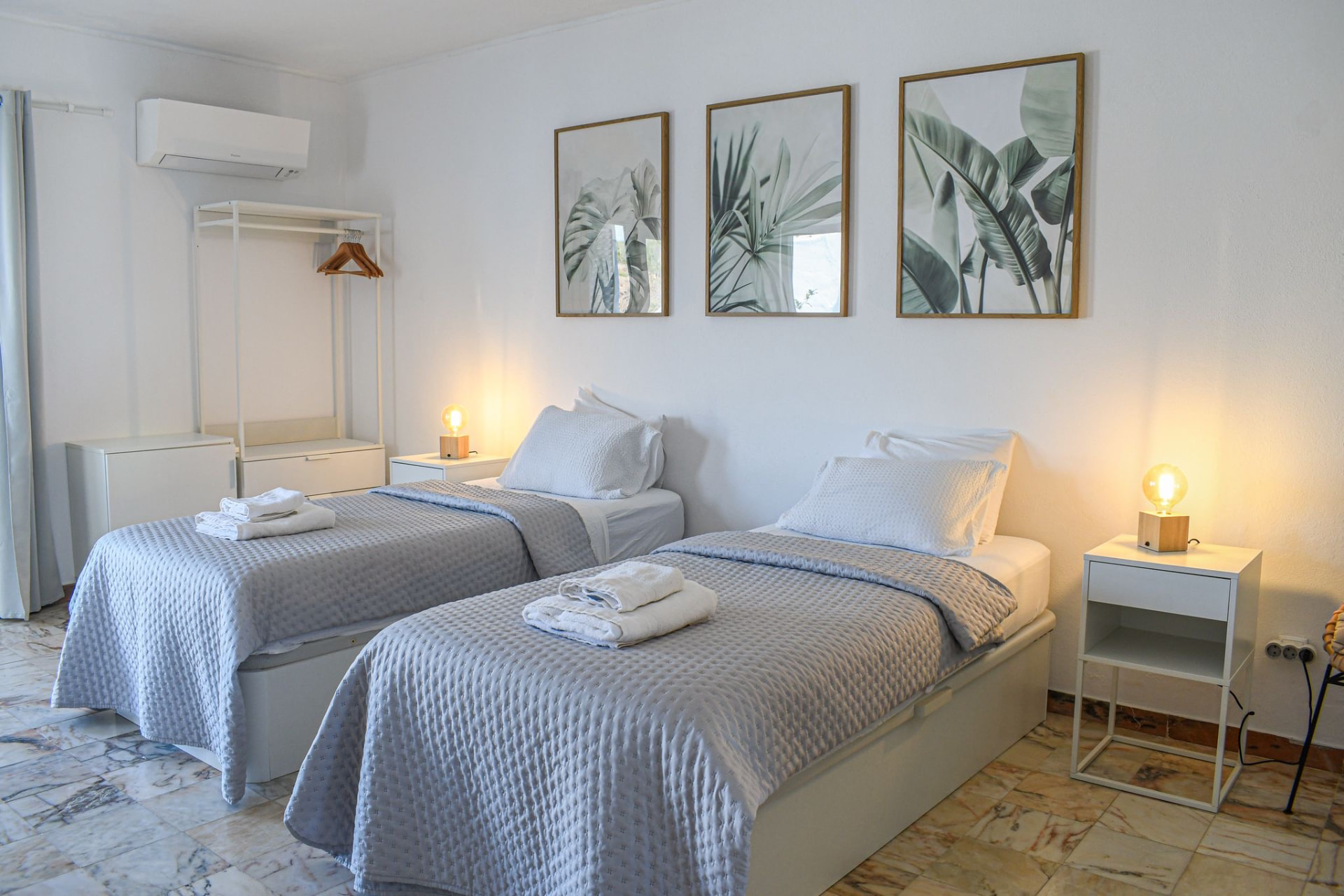 Twin bedroom with marble floors, warm lamps and leaf artwork