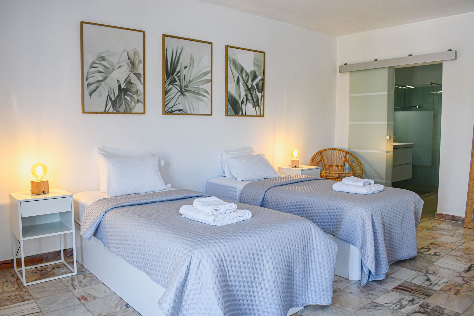 Twin bedroom with botanical prints and an en-suite bathroom