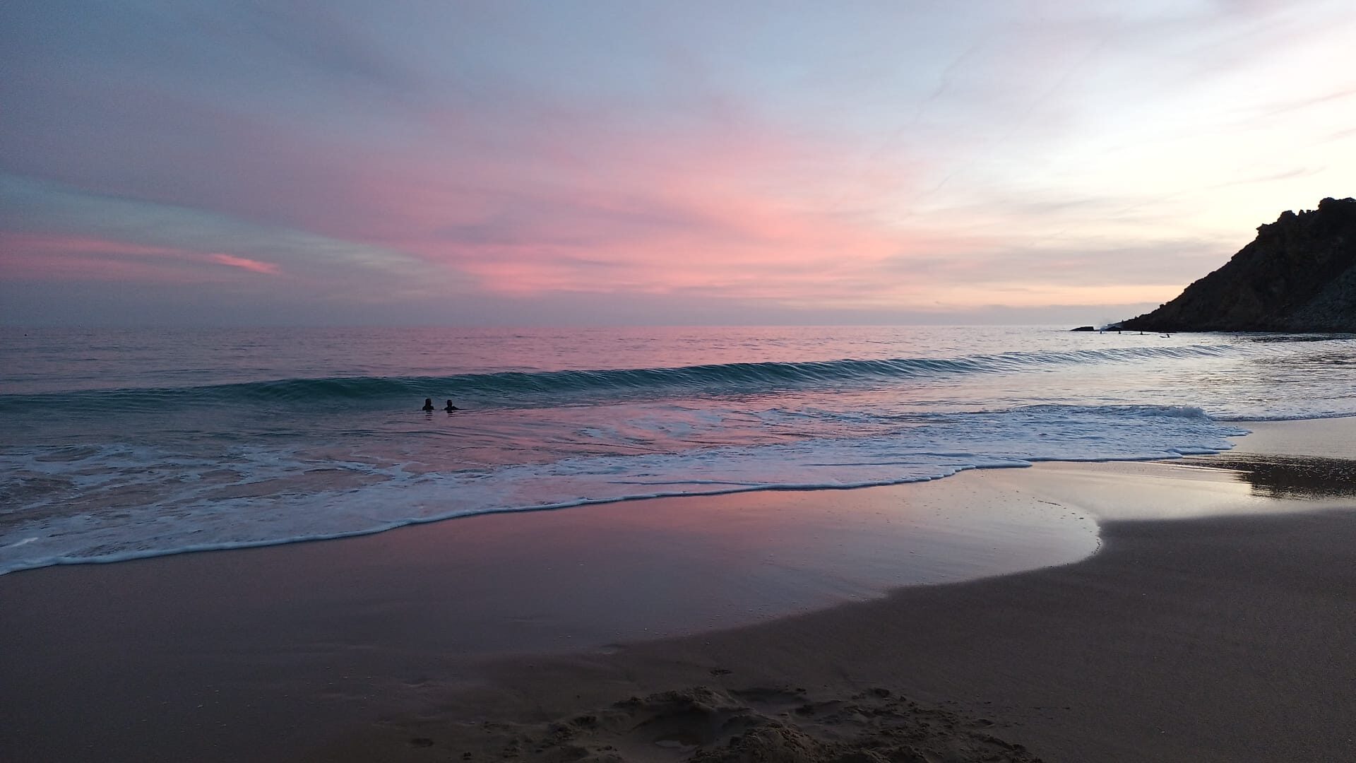Pink and gold sunset reflected on wet sand at low tide