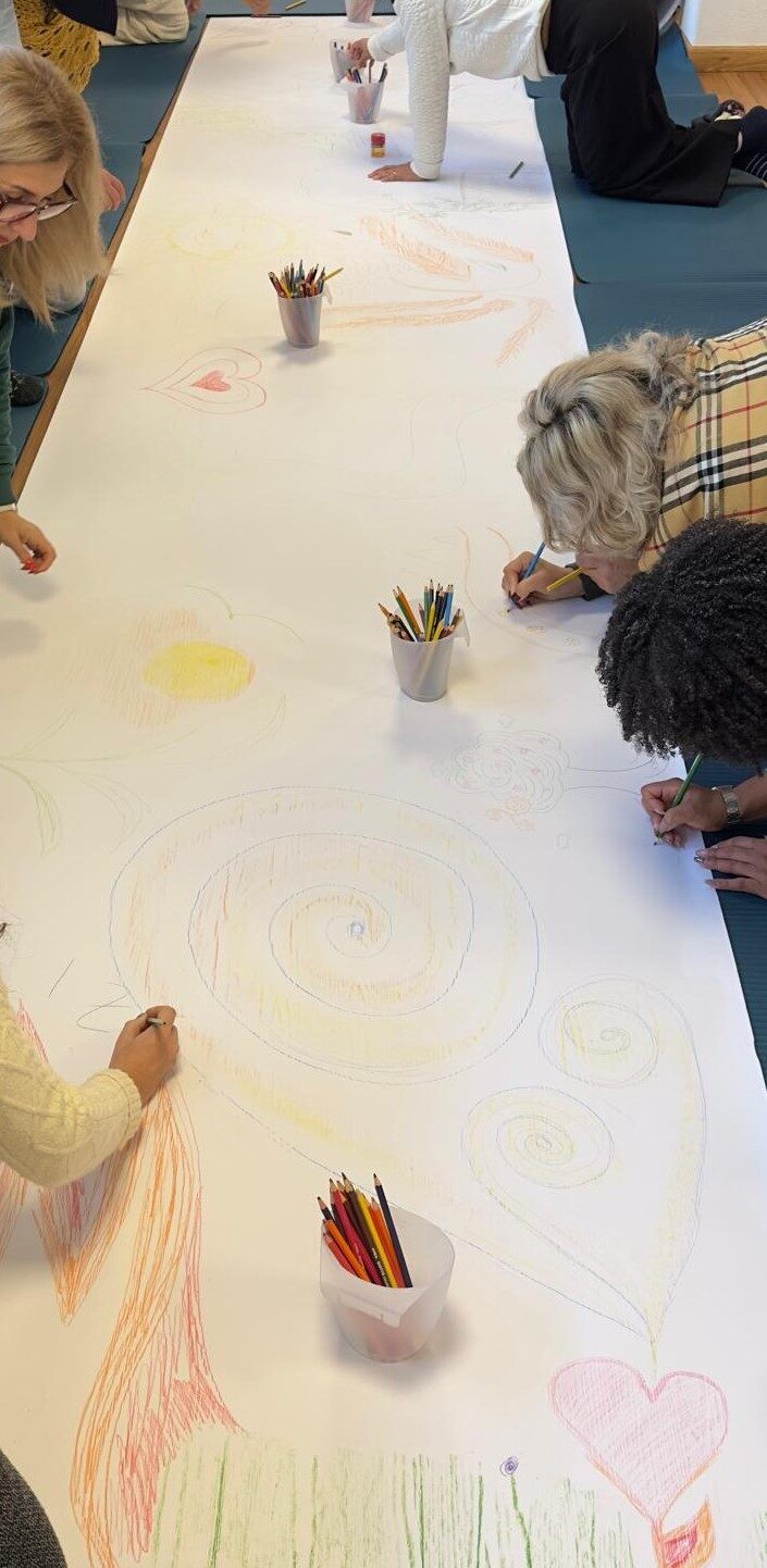 Hands drawing together in colour during a group session