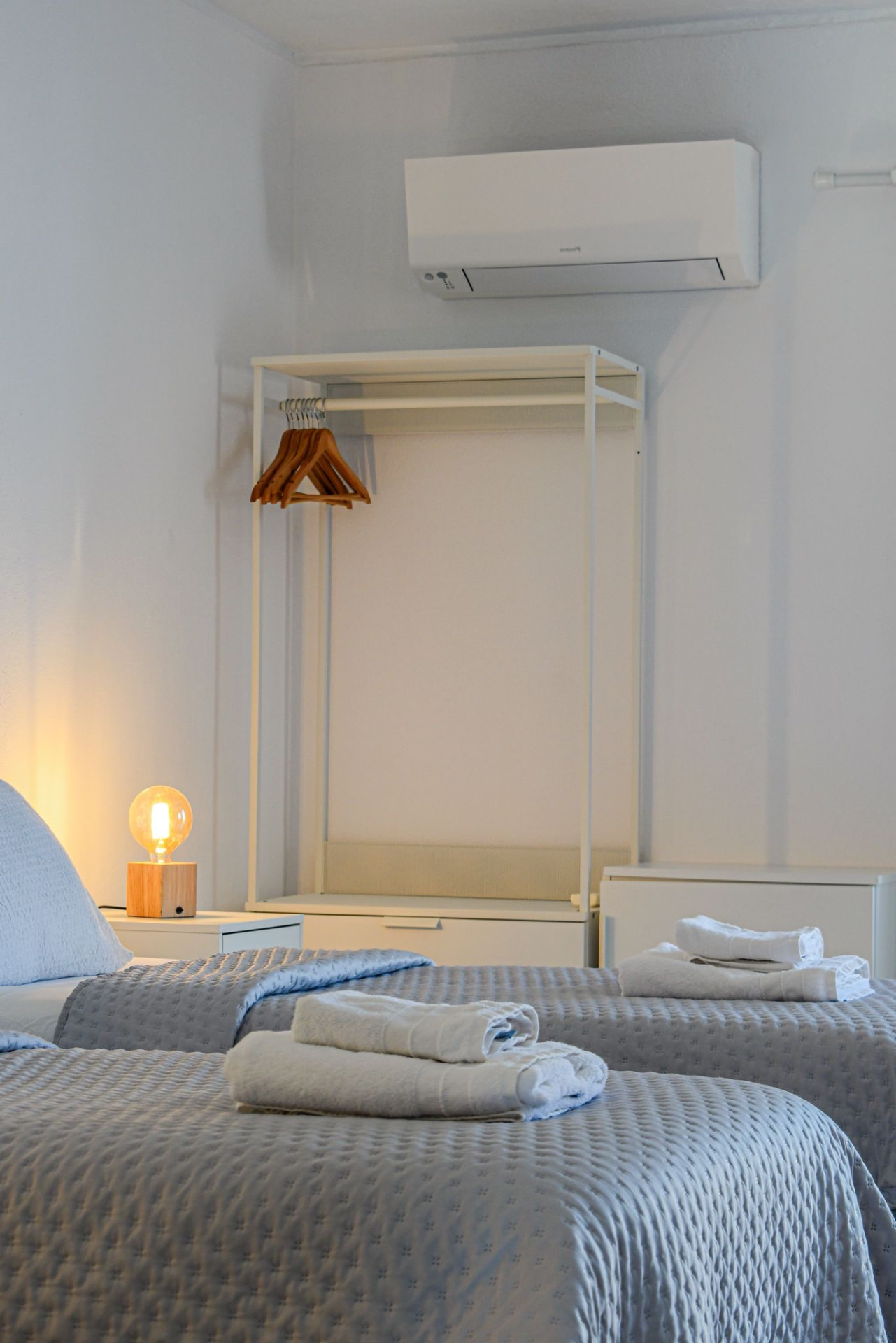 Bedroom detail with a warm bulb lamp, folded towels and open wardrobe