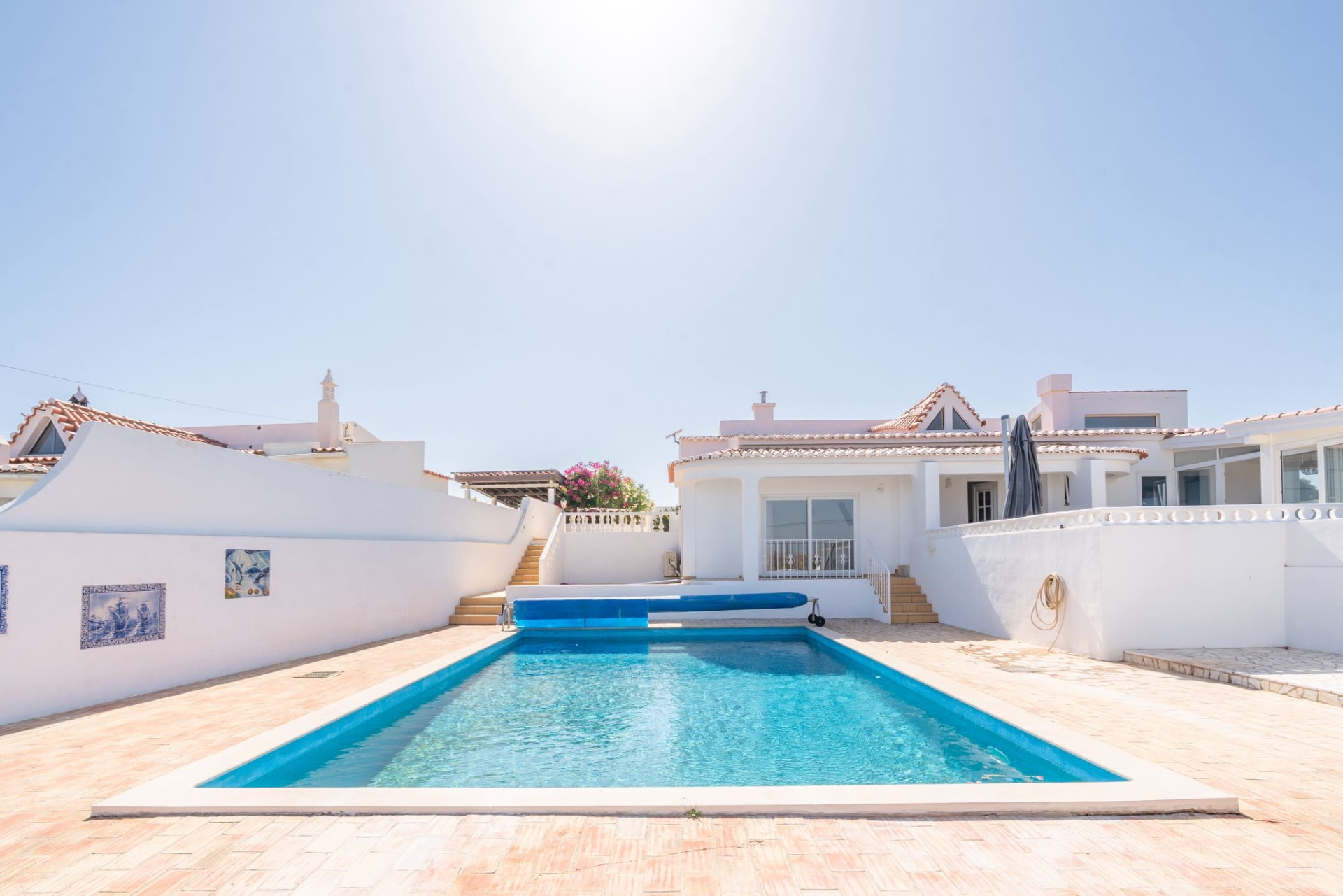 Whitewashed Algarve retreat house with a turquoise pool under clear blue sky
